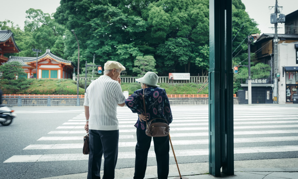 Picture of an elderly couple waiting to cross the road at a zebra crossing