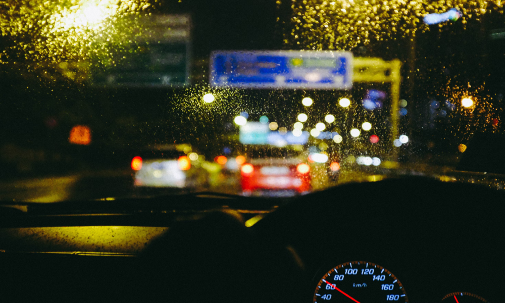 Image from inside a car at night, looking through the windscreen with rain drops on