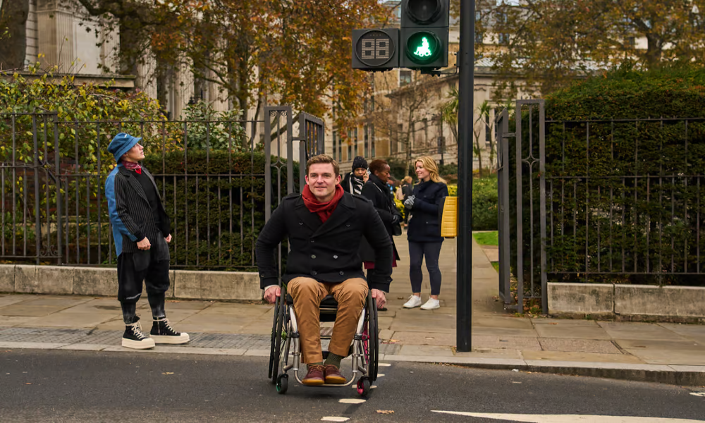Picture of a wheelchair user crossing a road at a signalised crossing
